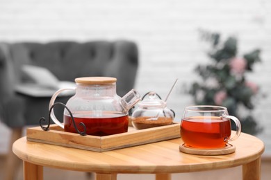 Teapot, cup of aromatic tea and brown sugar on wooden table indoors, space for text