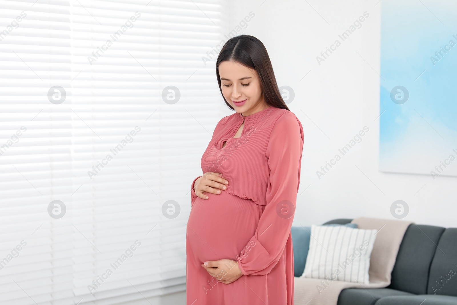 Photo of Beautiful pregnant woman in coral dress at home