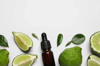 Photo of Glass bottle of bergamot essential oil and fresh fruits on white background, flat lay. Space for text