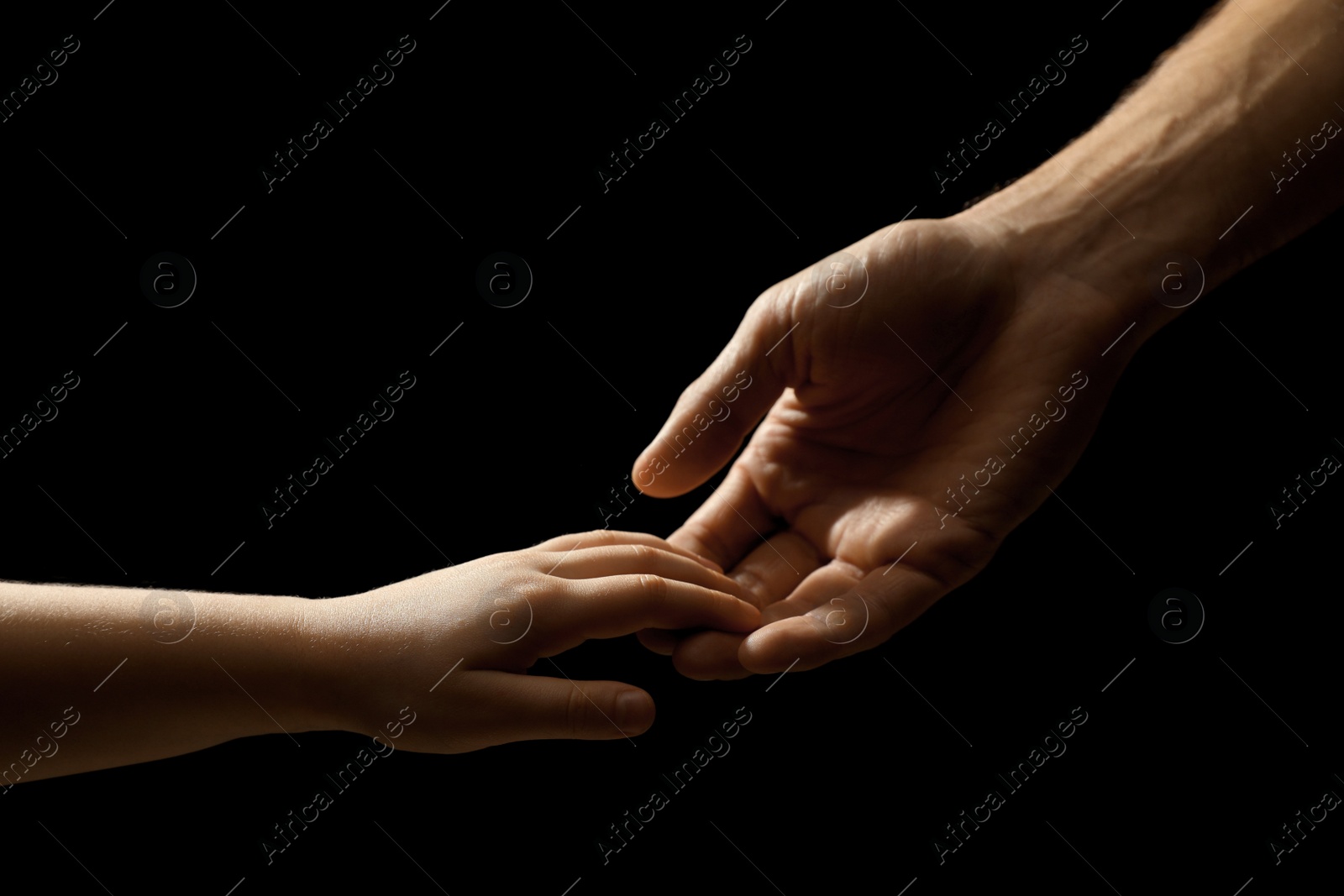 Photo of Man with child on black background, closeup of hands