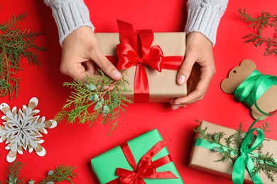 Photo of Woman wrapping Christmas gift on red background, top view