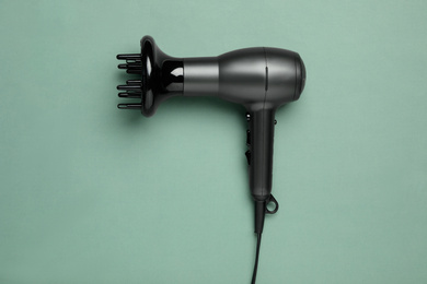 Hair dryer on green background, top view. Professional hairdresser tool