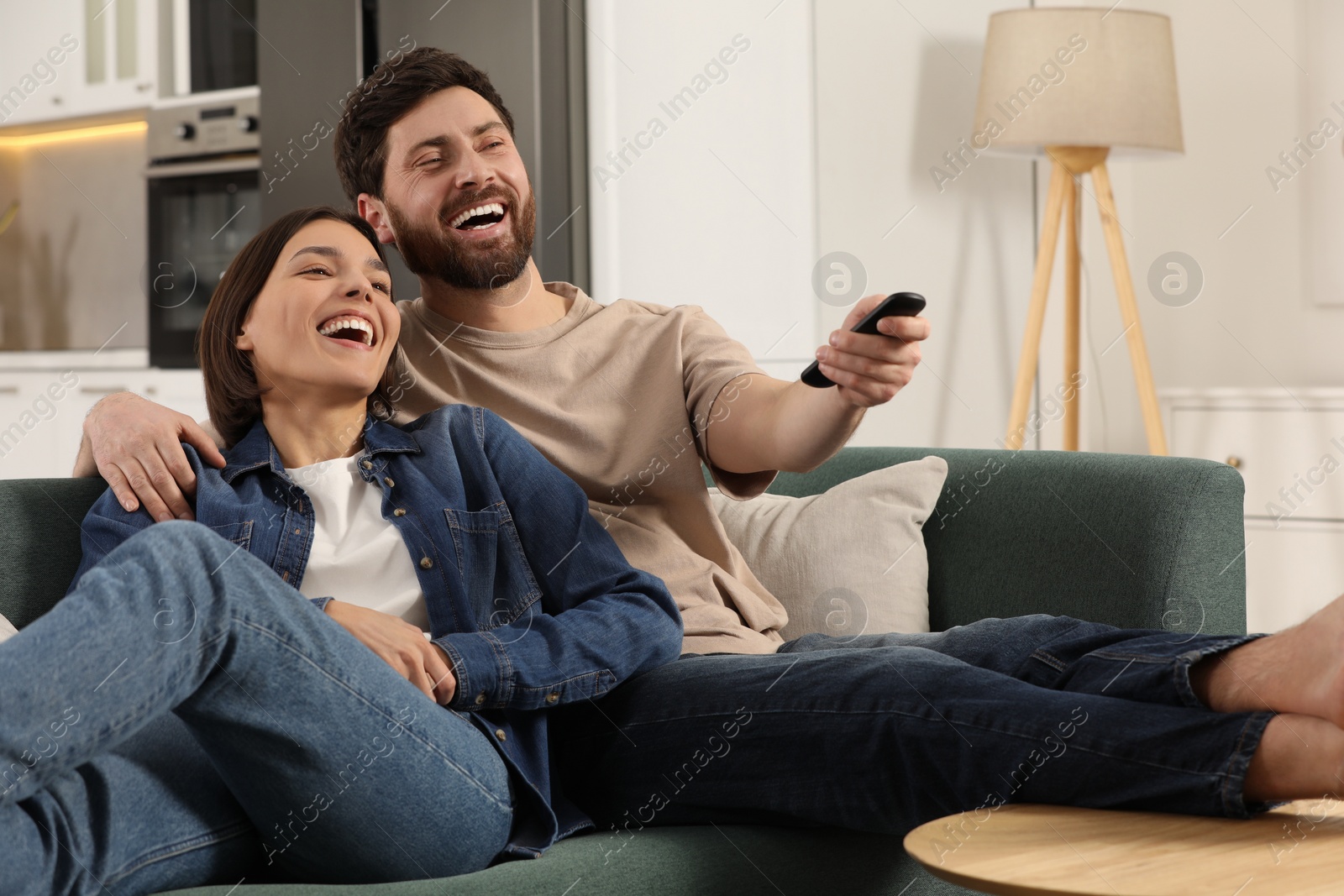 Photo of Happy couple watching TV on sofa at home