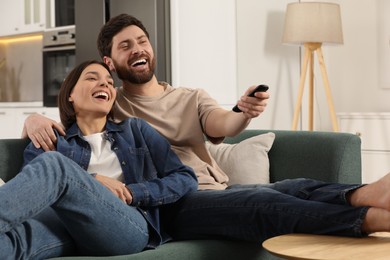 Photo of Happy couple watching TV on sofa at home