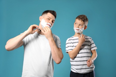 Photo of Dad shaving and son applying foam on blue background
