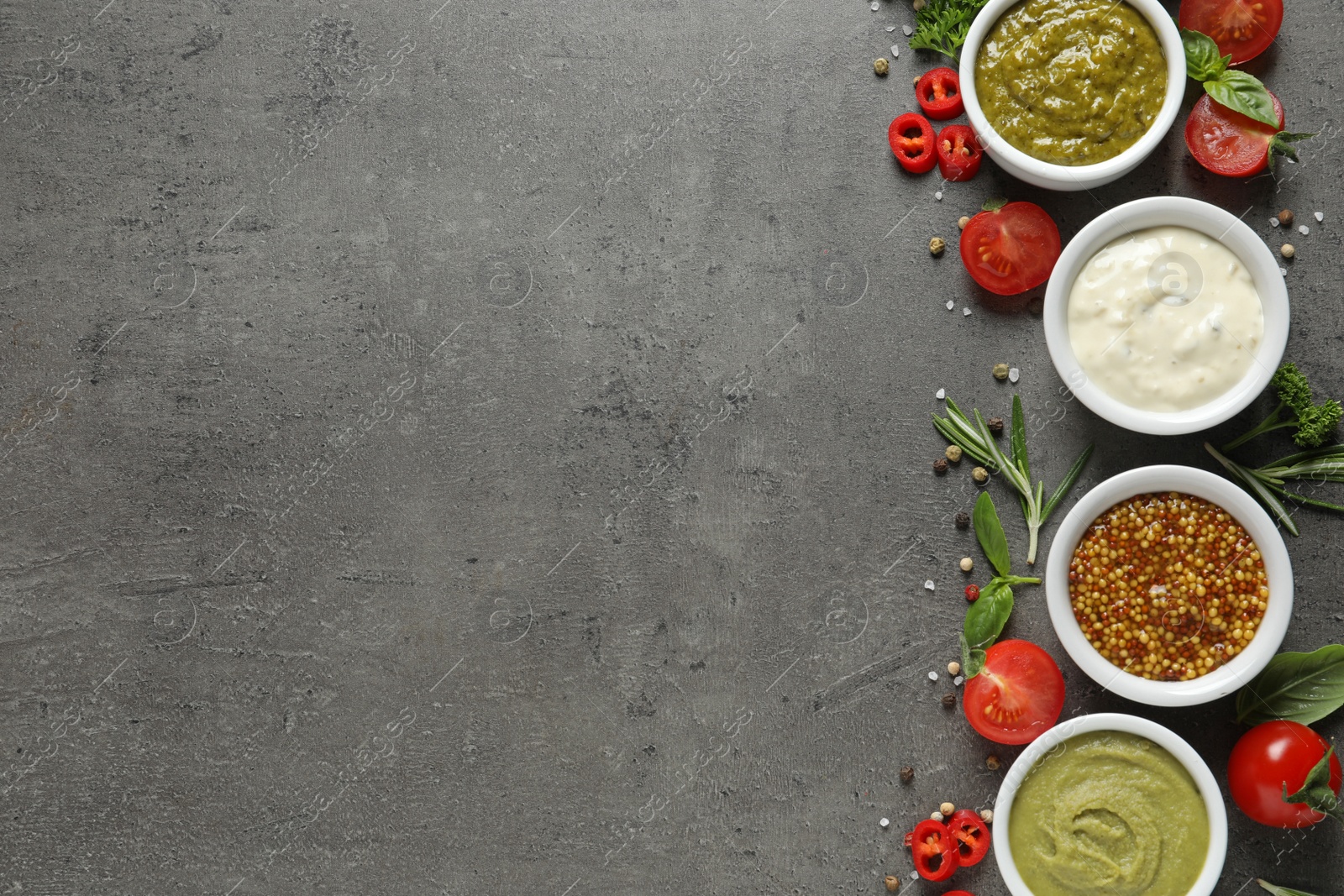 Photo of Bowls with different sauces and ingredients on gray background, flat lay. Space for text