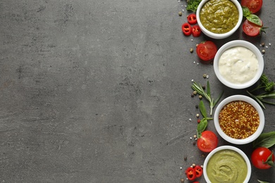 Photo of Bowls with different sauces and ingredients on gray background, flat lay. Space for text