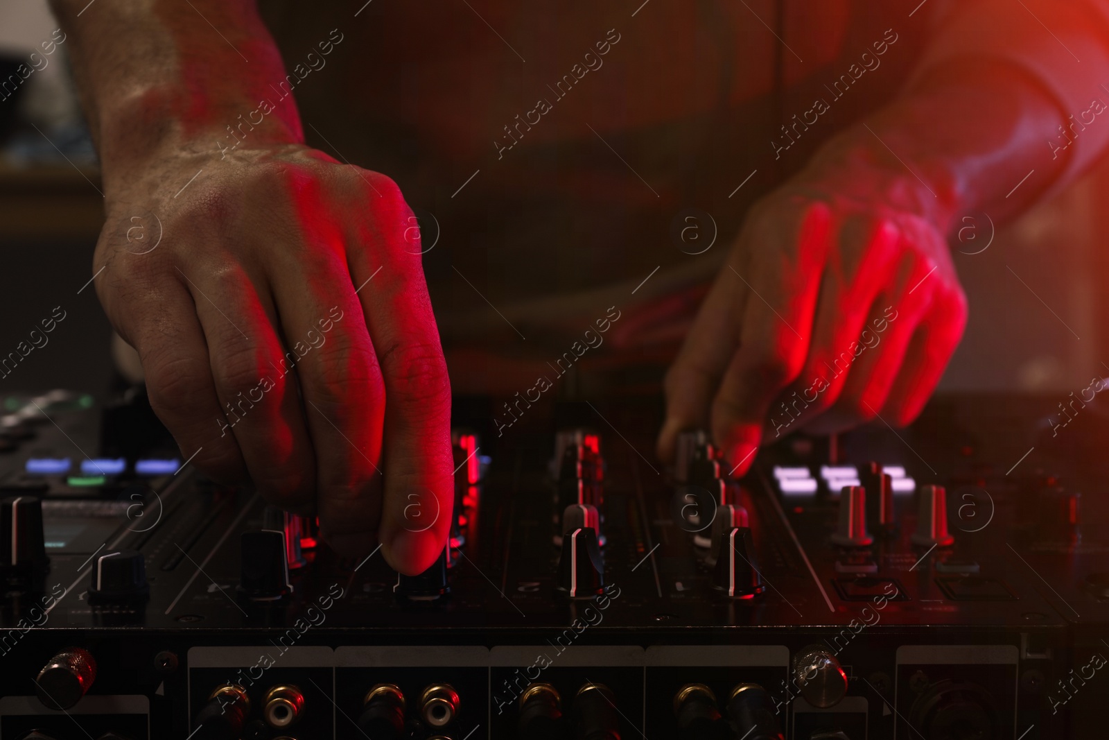 Photo of DJ creating music on modern console mixer in night club, closeup