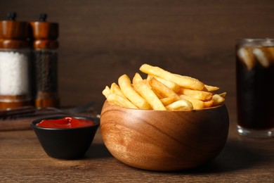 Photo of Delicious fresh french fries in bowl and tomato sauce on wooden table, closeup
