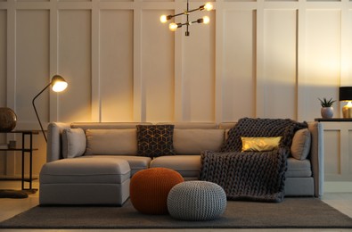 Photo of Living room interior with different stylish knitted poufs and sofa