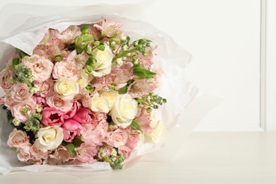 Beautiful bouquet of fresh flowers on wooden table near white wall, space for text