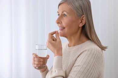 Photo of Beautiful woman taking vitamin pill at home