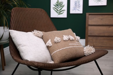 Photo of Comfortable wicker armchair with soft pillows in modern room. Interior design