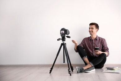 Young blogger recording video near light wall