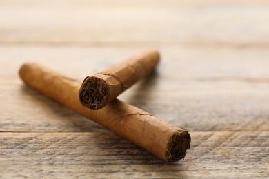 Cigars wrapped in tobacco leaves on wooden table, closeup. Space for text