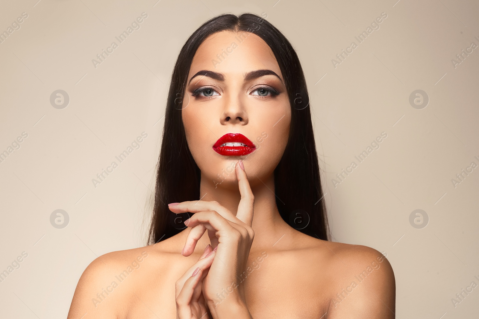 Photo of Portrait of beautiful young woman with red glossy lips on color background