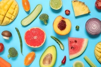 Flat lay composition with fresh organic fruits and vegetables on light blue background