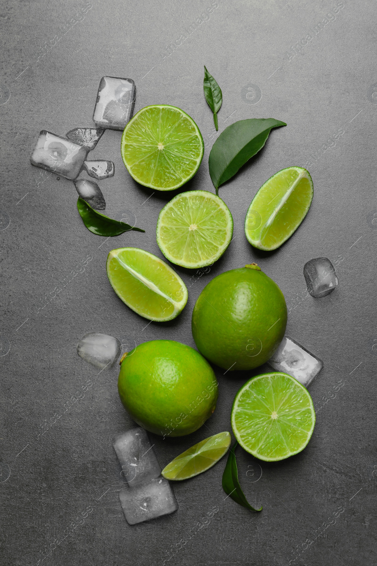 Photo of Fresh ripe limes and ice cubes on gray background, top view