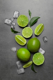 Photo of Fresh ripe limes and ice cubes on gray background, top view