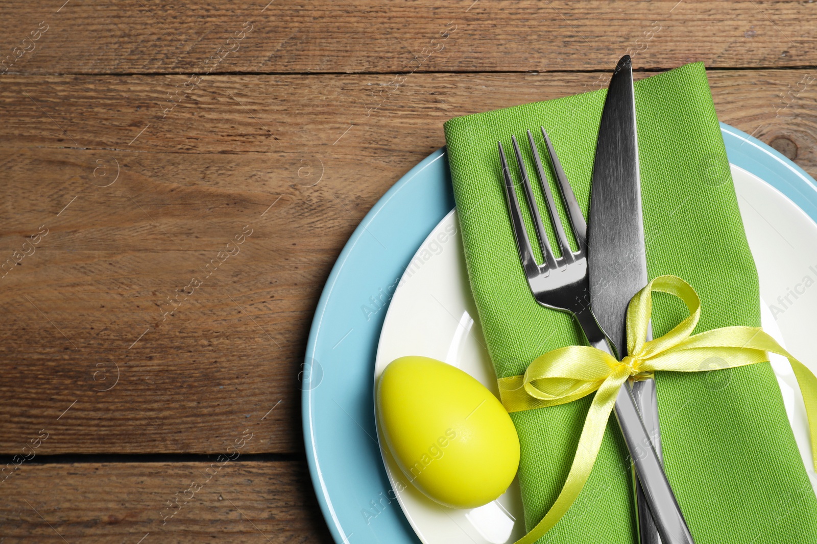 Photo of Festive table setting with painted egg and space for text, top view. Easter celebration