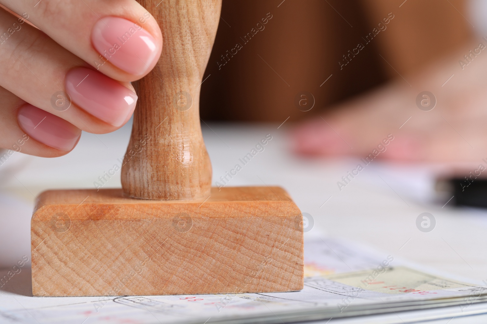 Photo of Ukraine, Lviv - September 6, 2022: Woman stamping visa page in passport at white table, closeup