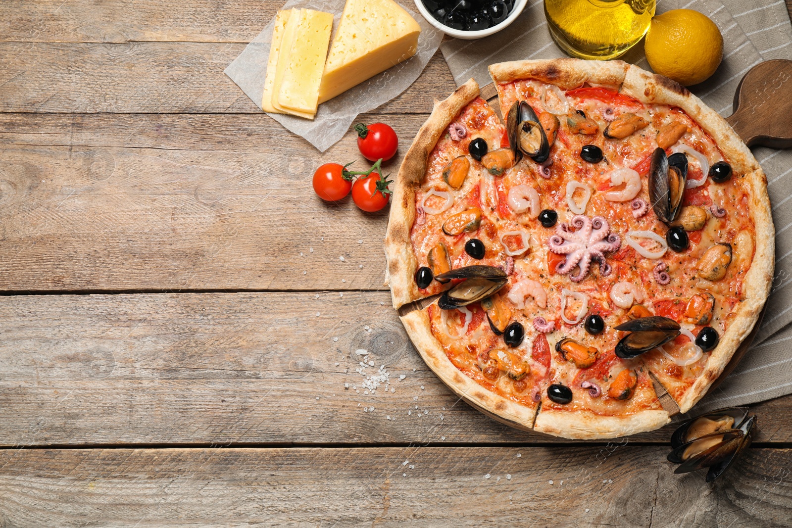 Photo of Tasty pizza with seafood and ingredients on wooden table, flat lay. Space for text