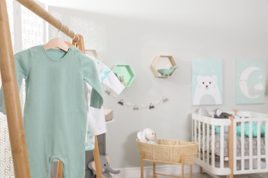 Photo of Cozy baby room interior, focus on wooden clothes rack