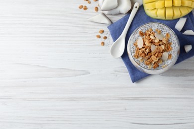 Delicious chia pudding with granola and mango on white wooden table, flat lay. Space for text