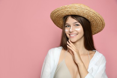 Photo of Teenage girl with sun protection cream on her face against pink background. Space for text