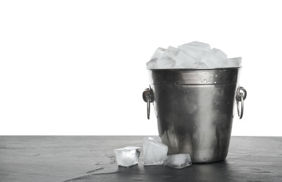 Metal bucket with ice cubes on table against white background