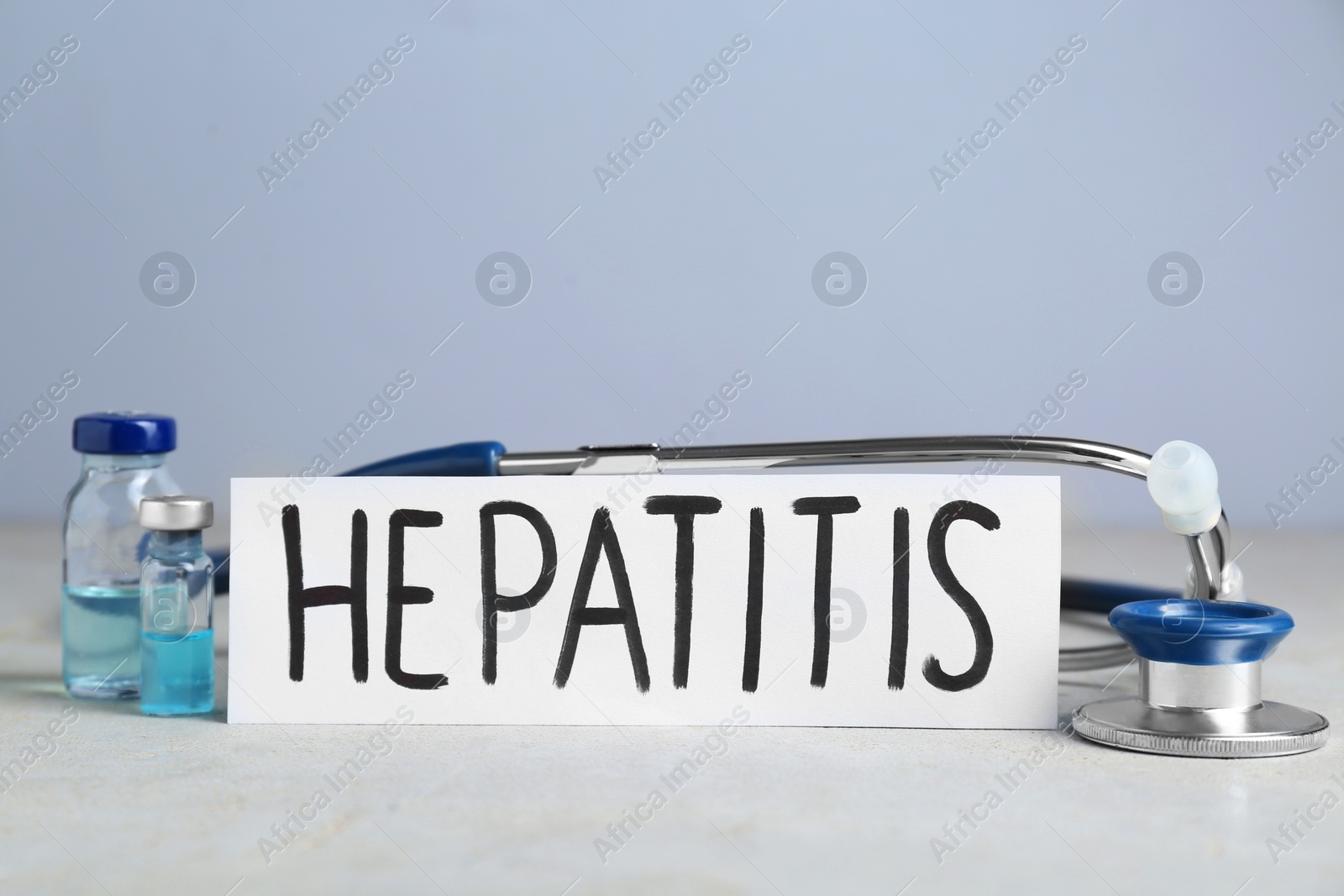 Photo of Word Hepatitis, vials and stethoscope on light grey table