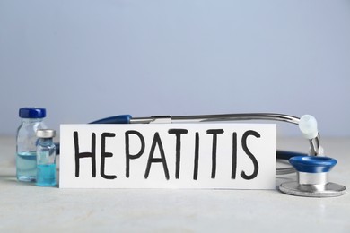 Word Hepatitis, vials and stethoscope on light grey table