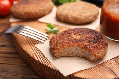 Delicious bitten vegan cutlet on wooden table, closeup