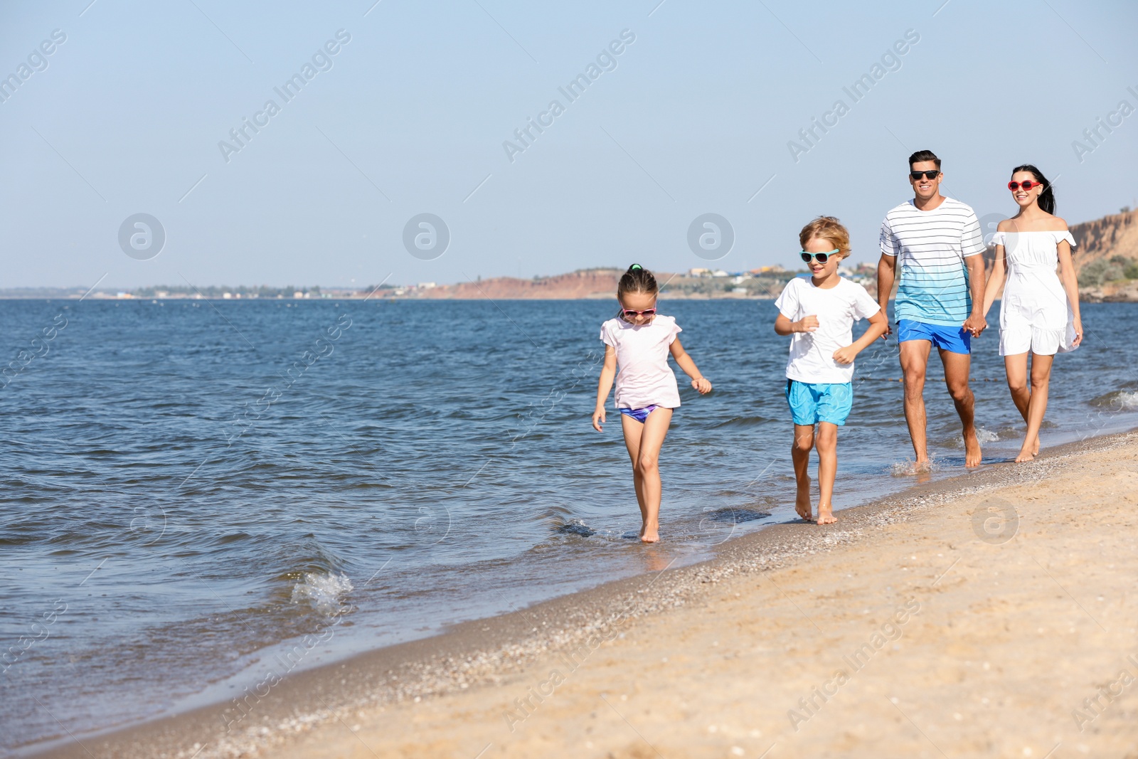 Photo of Happy family walking on sandy beach near sea. Summer holidays