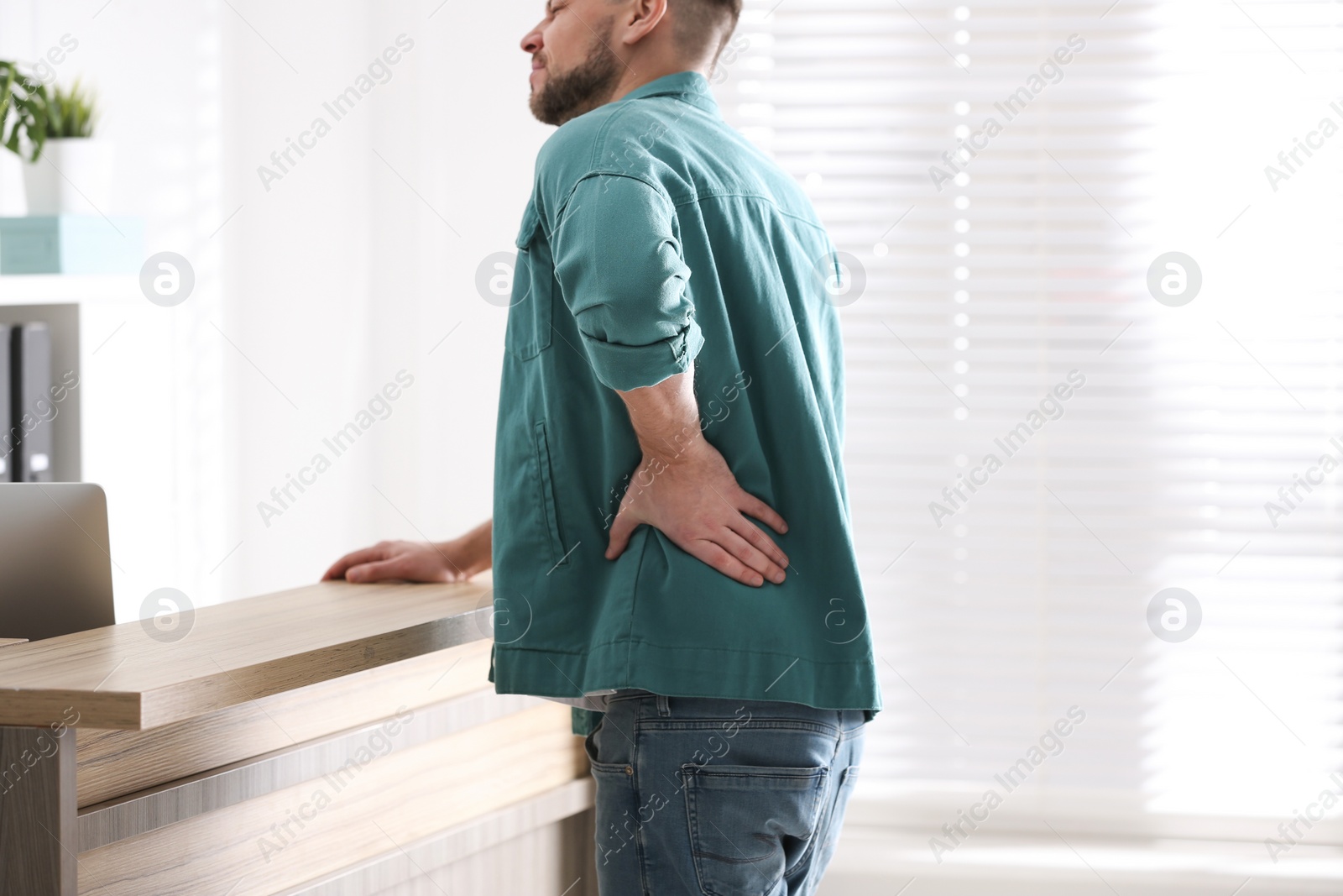 Photo of Man suffering from back pain in office, closeup. Bad posture problem