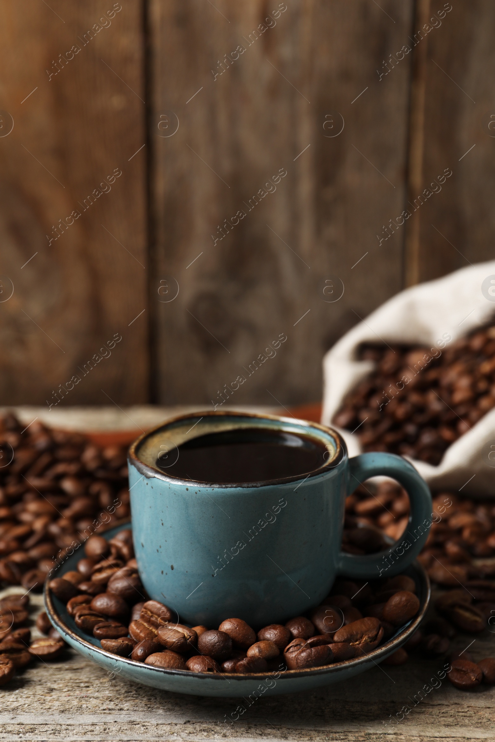 Photo of Cup of aromatic coffee and beans on wooden table