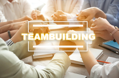 Image of People holding hands together at table. Teambuilding concept