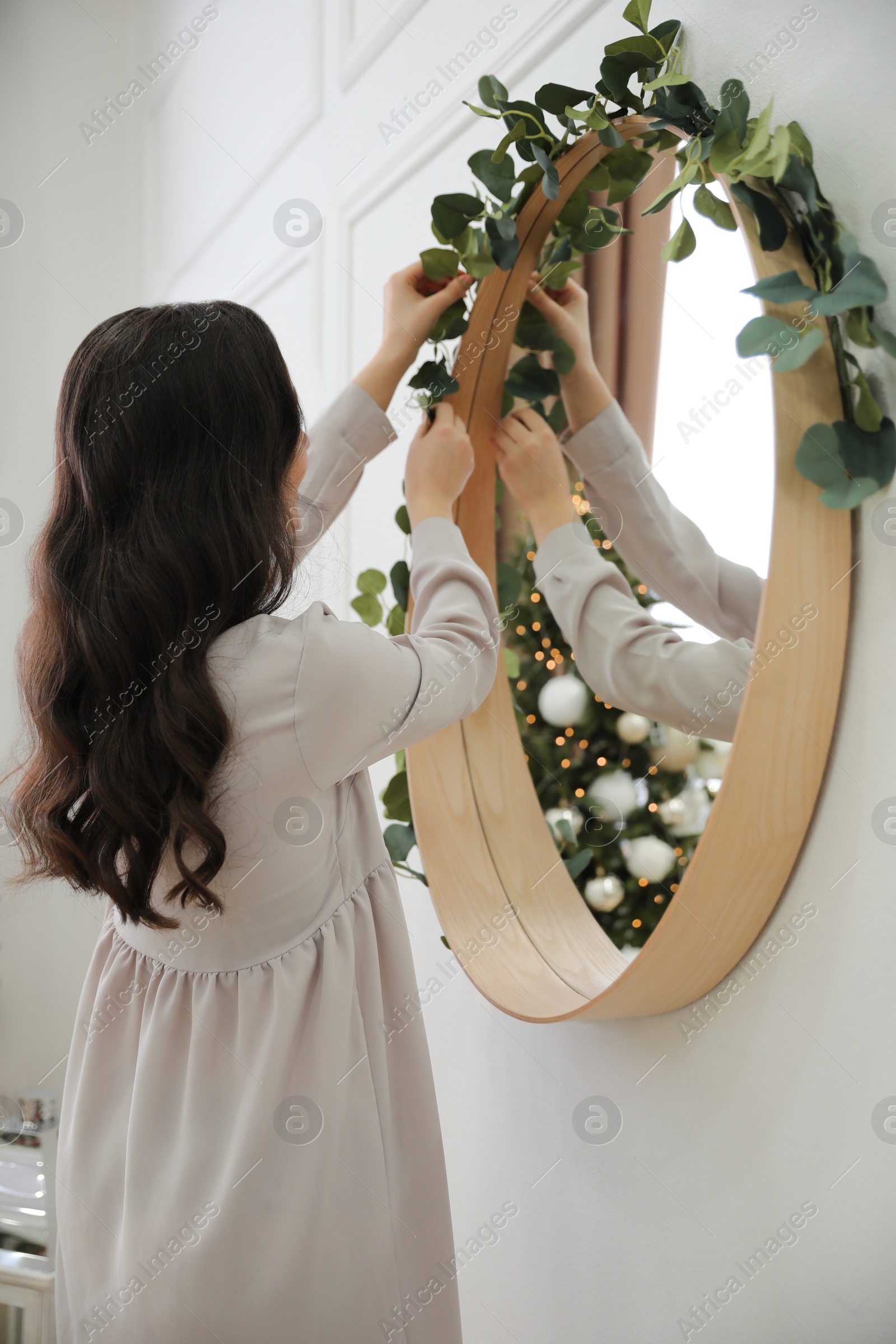 Photo of Woman decorating mirror with eucalyptus branches at home