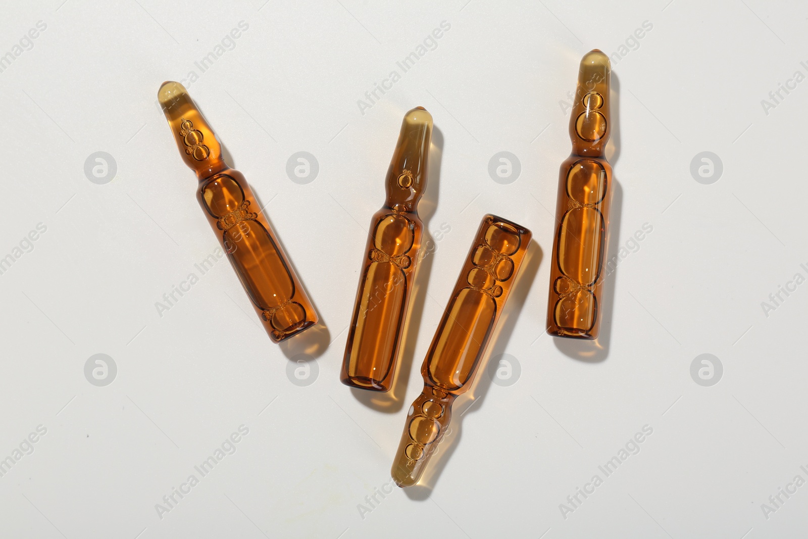 Photo of Glass ampoules with liquid on white background, top view