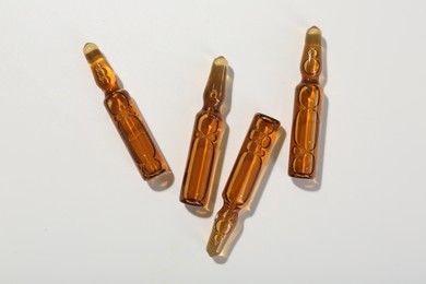 Photo of Glass ampoules with liquid on white background, top view