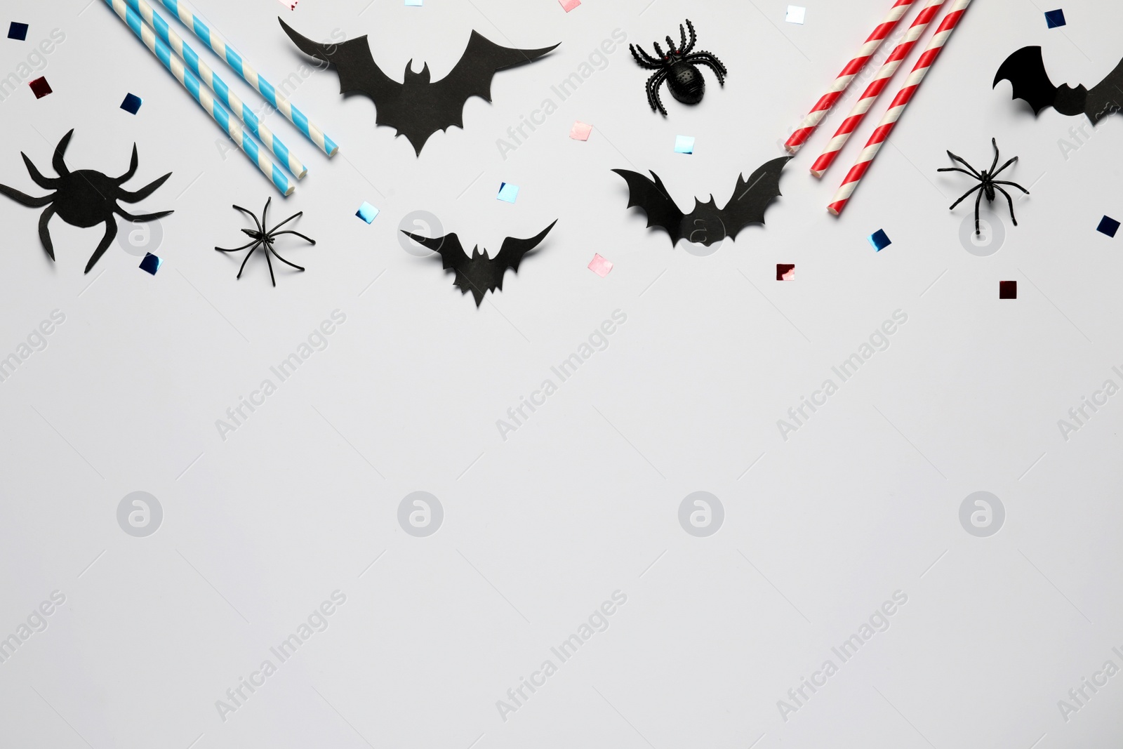 Photo of Flat lay composition with paper bats, spiders and straws on white background, space for text. Halloween celebration