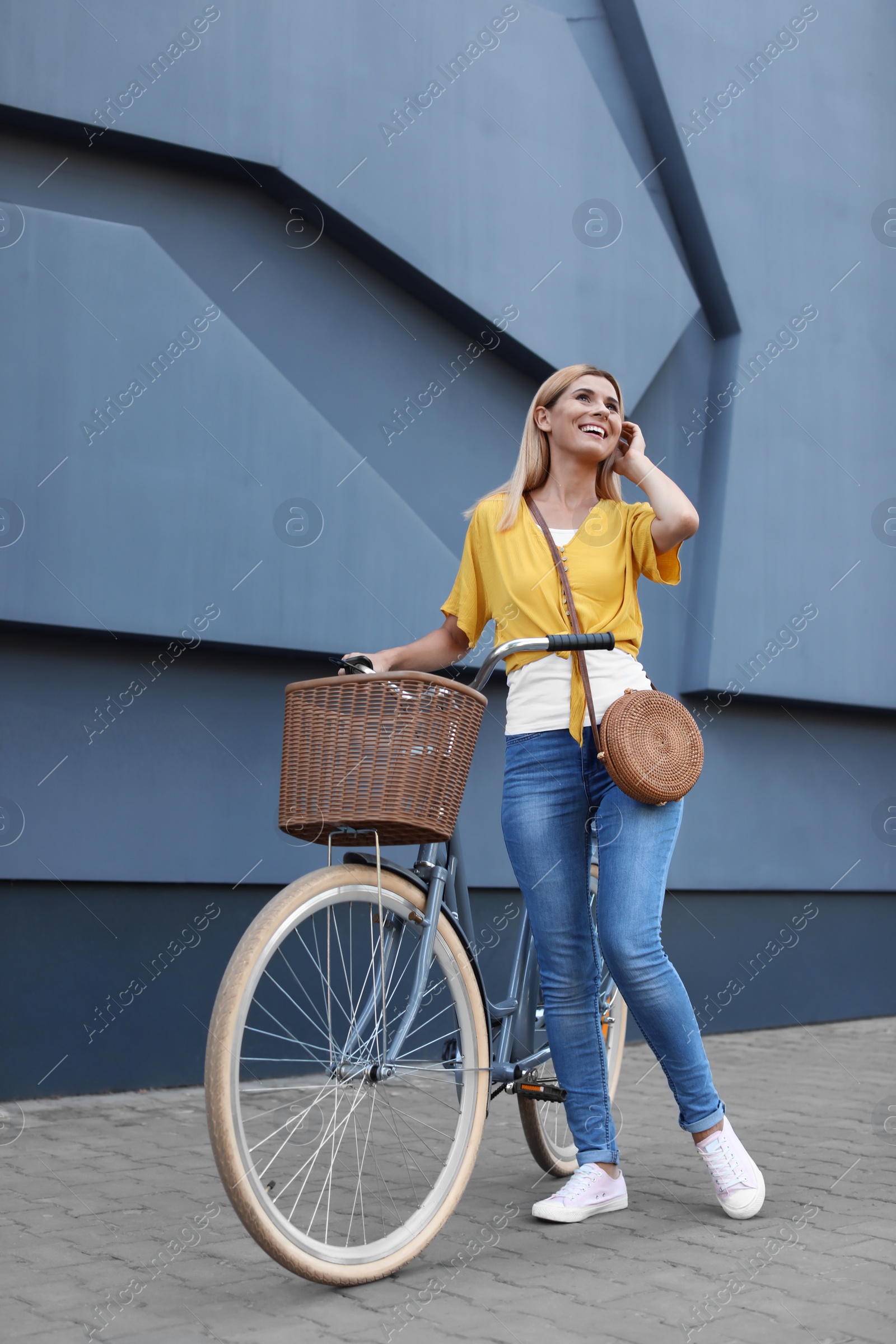 Photo of Woman with bicycle on street near gray wall