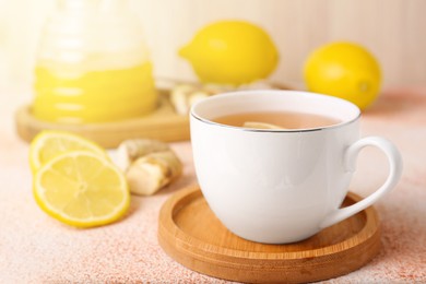 Photo of Tea, honey, lemon and ginger on beige textured table, closeup