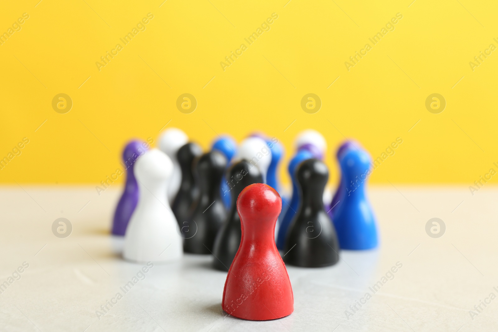 Photo of Red game piece near group of others on white table, closeup. Career promotion concept