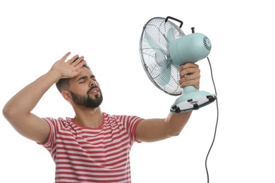 Photo of Man with fan suffering from heat on white background. Summer season