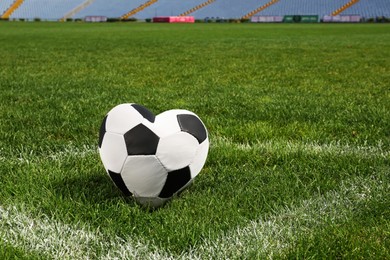 Image of Heart shaped soccer ball on green field at stadium