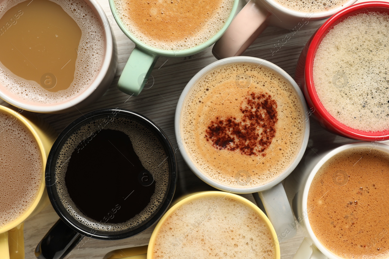 Photo of Many cups with different aromatic coffee on wooden table, flat lay