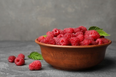 Bowl with delicious ripe raspberries on stone surface, space for text