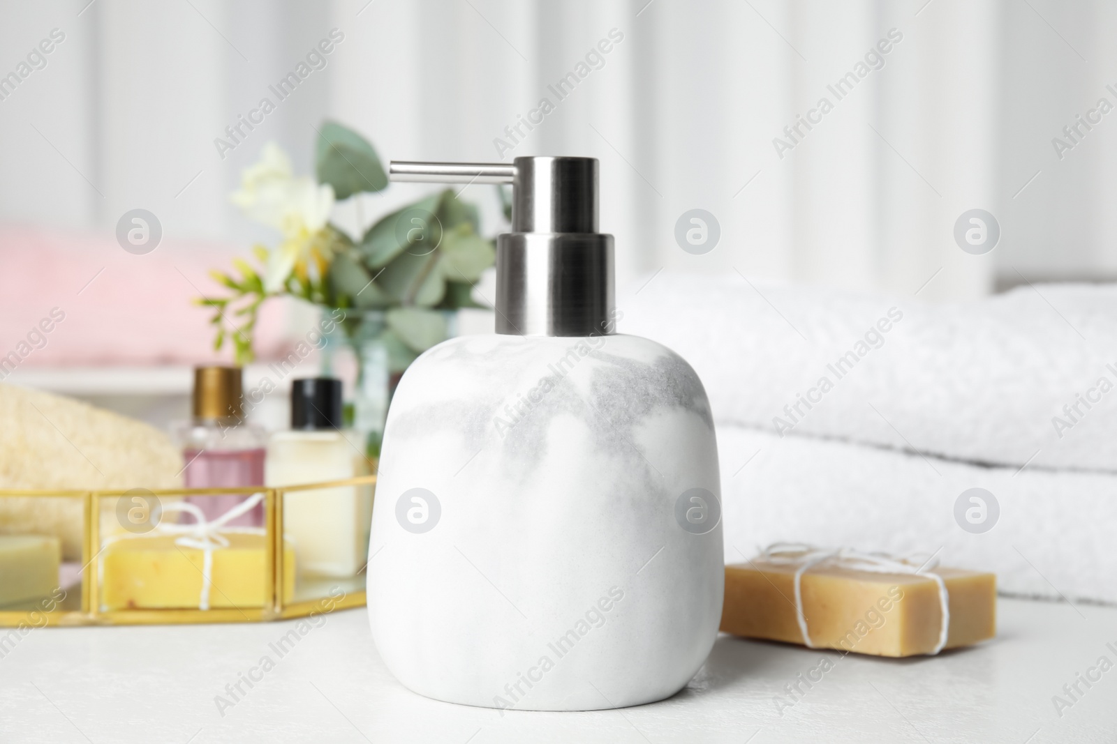 Photo of Marble soap dispenser and toiletries on white table