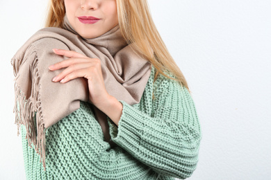 Image of Young woman wearing warm sweater and scarf on white background, closeup